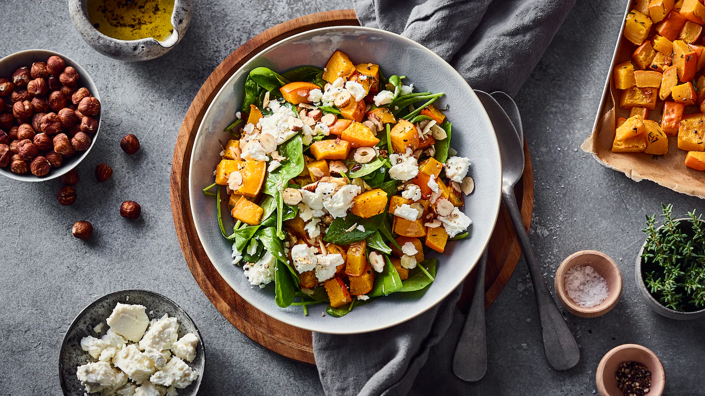 edeka-lauwarmer-kuerbis-spinat-salat-mit-haselnuessen Eine Schale mit Kürbis, Spinat, Feta und Haselnüssen