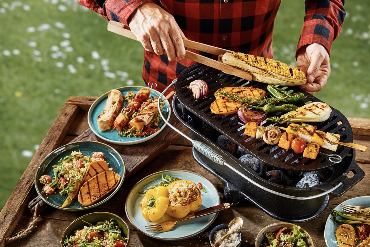 Man barbecuing vegetables over coals outdoors