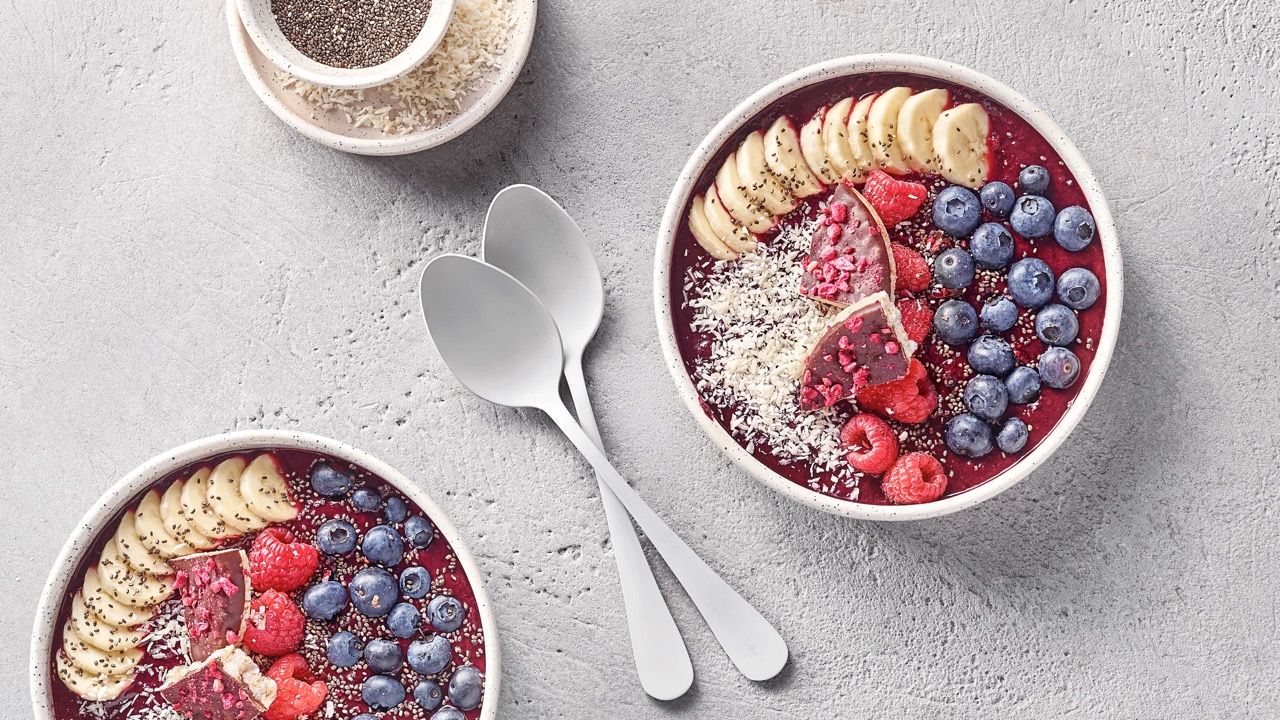 Eine bunte Aca Bowl mit verschiedenen Beeren und Banane als Dekoration