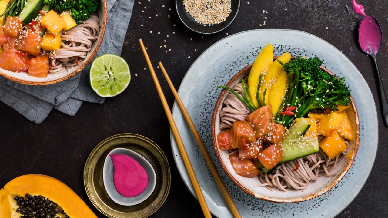 Poke-Bowl-Rezept Eine bunte Poke Bowl mit Nudeln, Lachs sowie verschiedenem Gemüse und Obst