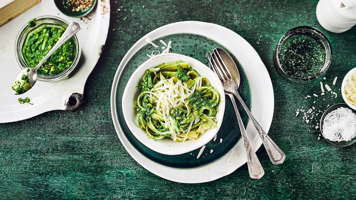 Grünes Grünkohl-Pesto in einer Schale, garniert mit Pinienkernen