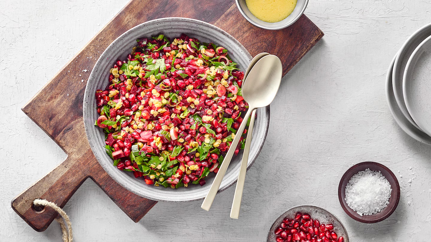 Rote-Bete-Linsen-Salat Eine Schüssel mit buntem Rote-Bete-Linsen-Salat, garniert mit Granatapfelkernen und frischen Kräutern