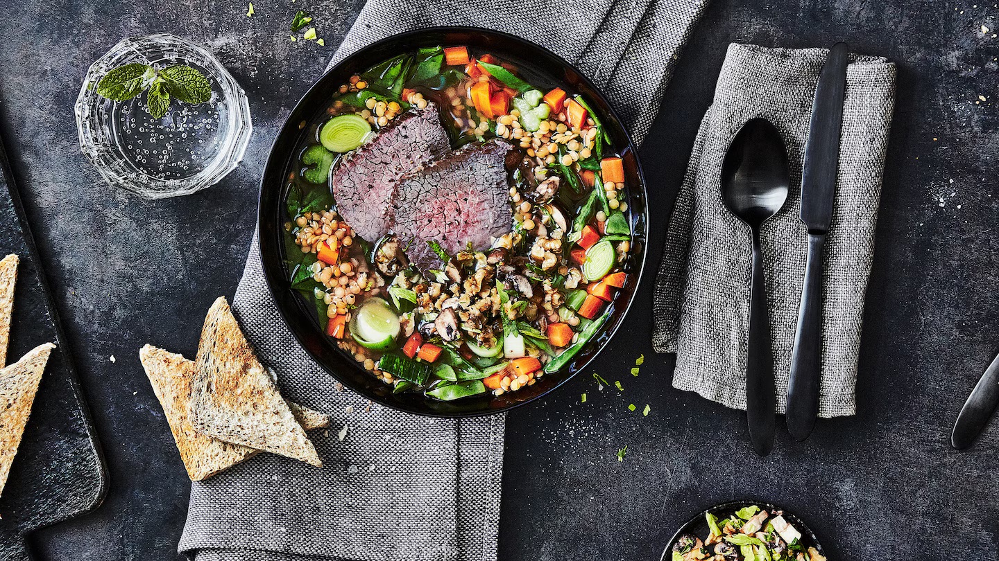 Eine Schüssel mit Rindfleisch-Eintopf mit Linsen, Karotten und Lauch