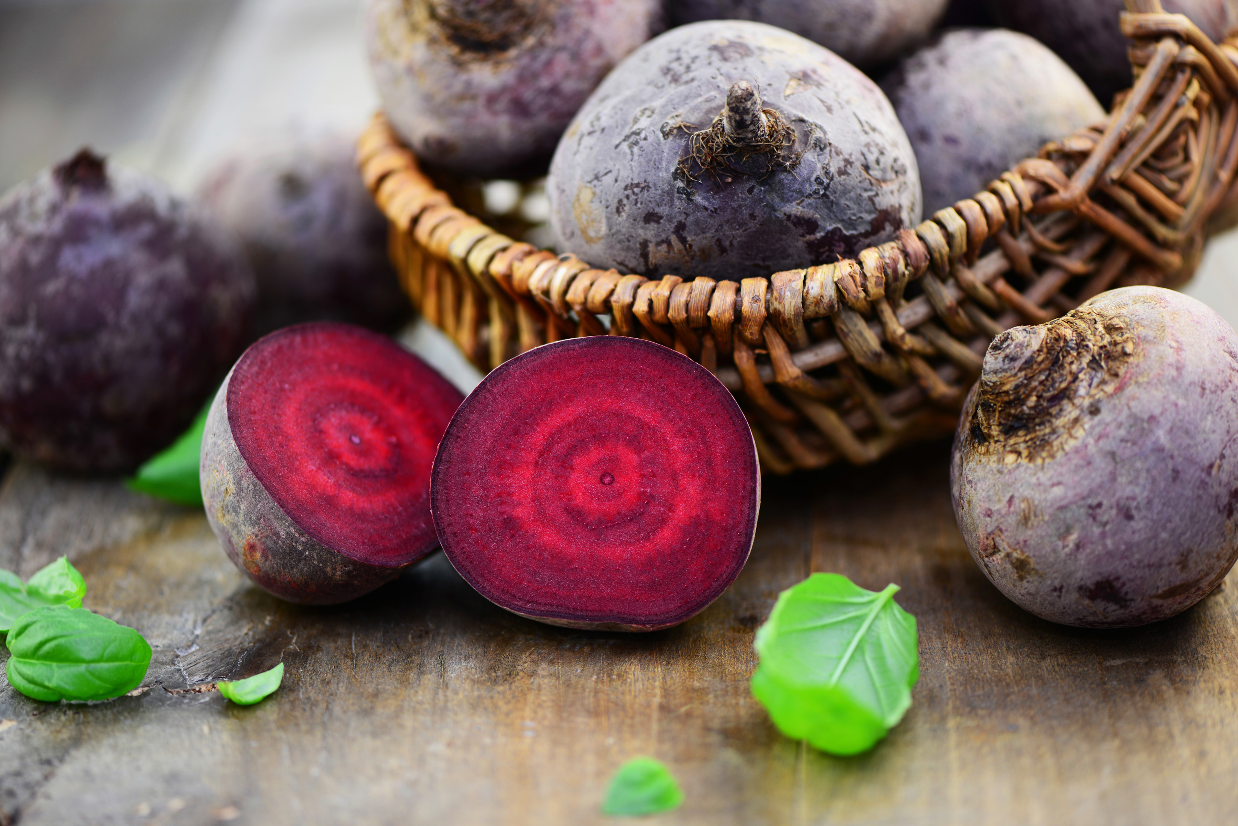 rote-bete-im-korb-und-davor-eine-aufgeshnitten Mehrere rote Bete in einem Korb, vor diesem liegt eine rote Beete aufgeschnitten