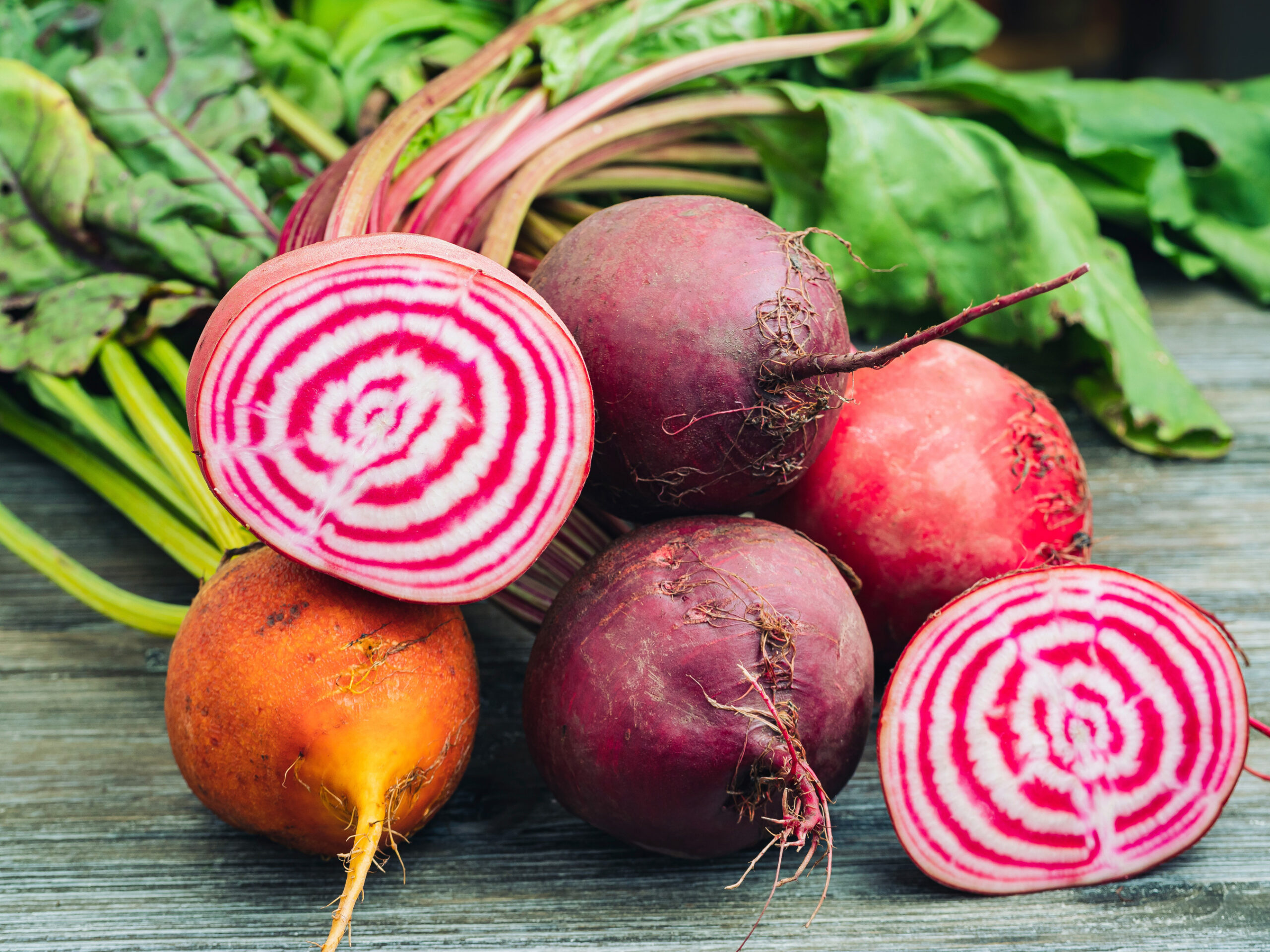 Rote-Bete-bunt Bunte rote Beete mit Blättern, eine ist aufgeschnitten